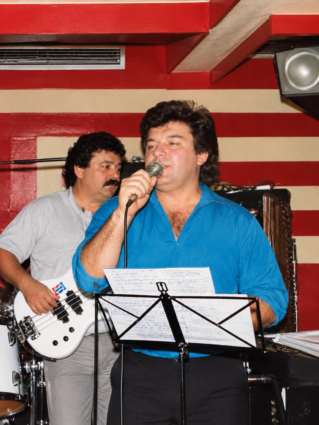 Cantor com camisa azul e músicos em palco